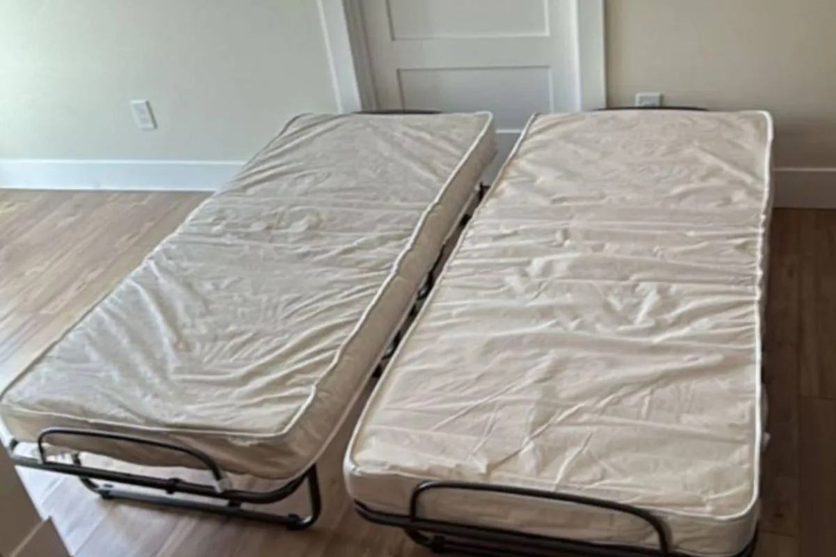 A simple room with two foldable beds arranged side-by-side, set up for additional guests. The room is bright and functional, suggesting a practical yet comfortable solution for larger groups or families needing flexible sleeping arrangements.