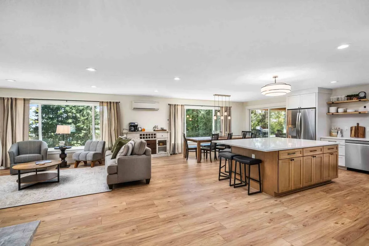 The hero image showcases a beautifully remodeled, open-concept interior featuring a spacious kitchen island, a stylish dining table, inviting seating area, and floor-to-ceiling windows that flood the space with natural light and idyllic vineyard views. The scene feels warm and inviting, perfect for gatherings, cooking, or simply relaxing with friends and family.