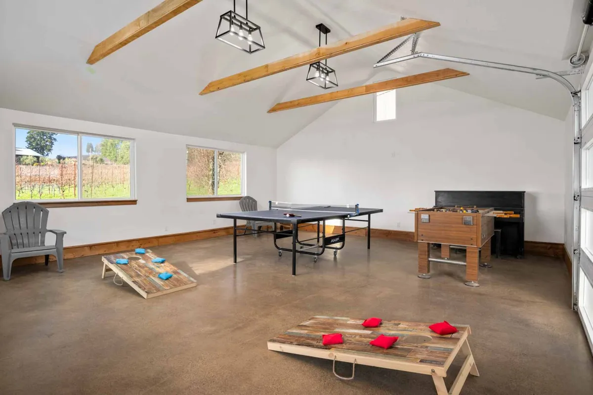 This image captures a vibrant game room setup with a ping pong table, foosball table, and a cornhole game. Adirondack chairs are arranged for seating, and the mood is lively and relaxed, reflecting a space designed for fun and friendly competition.